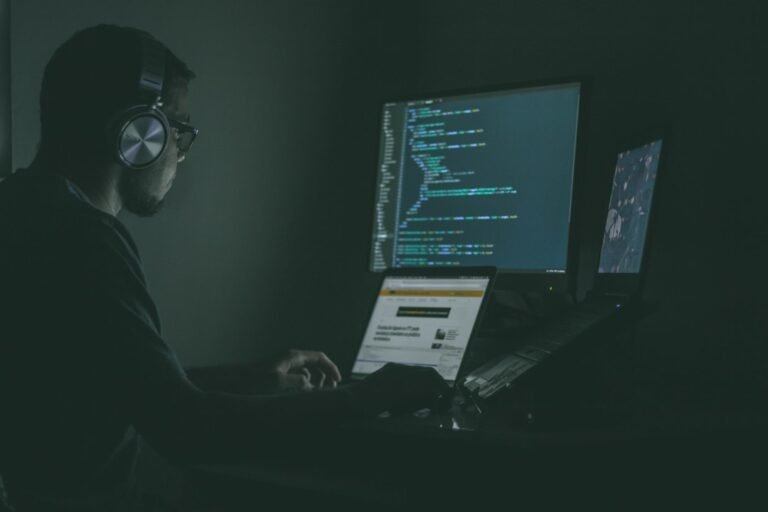 Profissional trabalhando em computadores, imagem ilustrativa para investigação de invasão envolvendo agente de IA