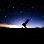 Telescópio sob céu estrelado, imagem ilustrativa para notícia sobre impacto de espelhos espaciais no céu noturno